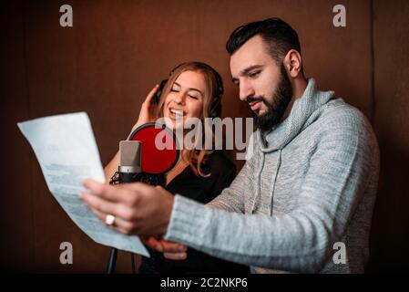 Produttore di musica mostra testo al cantante femminile nelle cuffie, song record in music studio. Cantante femminile Registrazione traccia audio. Professional Audio digitale Foto Stock