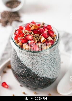 Colazione salutare concetto e idea - due colori chia pudding con materie organiche melograno, mandorla e grani di canapa. Il vasetto di vetro con il nero di carbone vegetale e w Foto Stock
