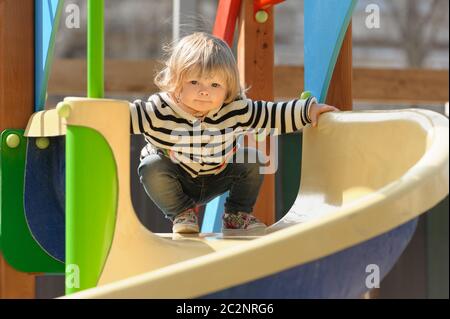 carina bambina che scivola giù per lo scivolo dei bambini Foto Stock