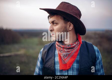 Ritratto di brutale cowboy in giacca di pelle e cappello, occidentale. Vintage persona maschile, retrò moda americana nel selvaggio west style Foto Stock