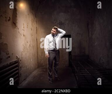 Uomo d'affari in piedi in una vecchia prigione scura Foto Stock