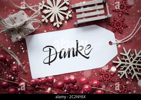 Una etichetta con il tedesco Calligraphy Danke significa Grazie. Natale Rosso Deocration simili Sled, presente e Snowlfakes Foto Stock