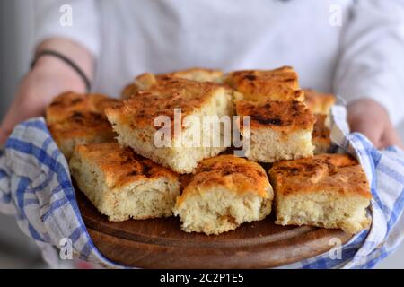 Mani femminili che tengono pane appena sfornato/ focaccia italiana fatta in casa con rosmarino e olio d'oliva/ appena sfornata e pronta a mangiare Foto Stock