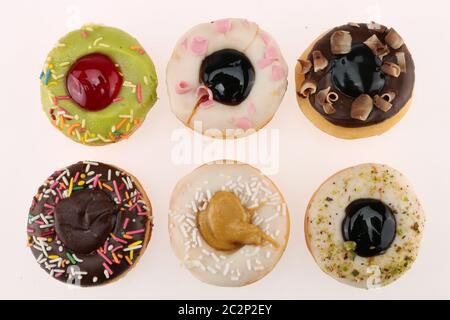 Ciambelle set isolato su bianco. Diverse tipologie di ciambelle: Al cioccolato, rosa a strisce, con smalto e spruzzi colorati e biscotto nero spruzzato Foto Stock