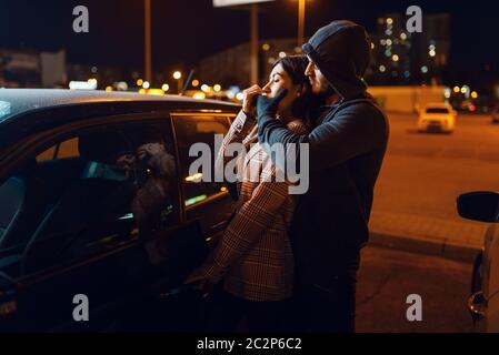 Femmina driver e hijacker in auto, criminale, ladro. Dirottamento al veicolo in parcheggio. Rapina automatica, criminalità automobilistica, dirottamento Foto Stock