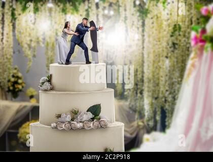 Torta nuziale, sposa e sposo figurine sulla parte superiore, simbolo di matrimonio. Torta per sposi novelli con piccole figure Foto Stock