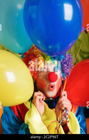 Clown sorridente con un mazzo di palloncini colorati Foto Stock