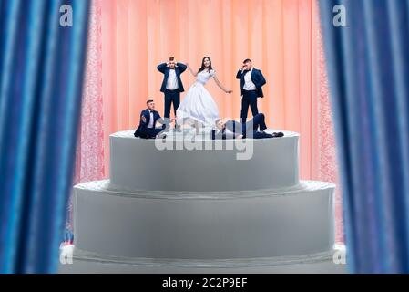 Torta di nozze, sposa e molti figurines grooms sulla parte superiore. Torta fittizia per sposi novelli con piccole figure Foto Stock