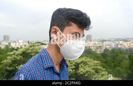 Vista laterale dell'uomo che indossa la maschera facciale sullo sfondo della città. Foto Stock