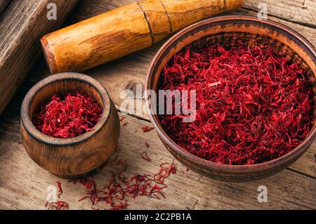 Spezia di zafferano rosso organico grezzo su sfondo di legno Foto Stock