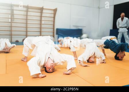 Bambini judo, kids in kimono pratica delle arti marziali in palestra. Bambini e bambine in uniforme sulla formazione sportiva Foto Stock