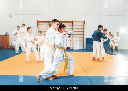 Kid judo, corsi di formazione per bambini arte marziale nella hall. Ragazzi piccoli in uniforme, giovani combattenti Foto Stock