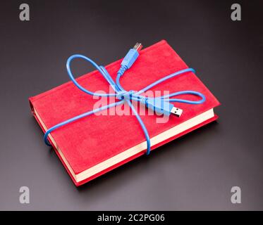 Blue Ribbon dal cavo usb sul libro come un presente Foto Stock