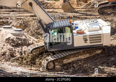 Escavatore bianco a terra durante la costruzione della strada, vista ravvicinata Foto Stock