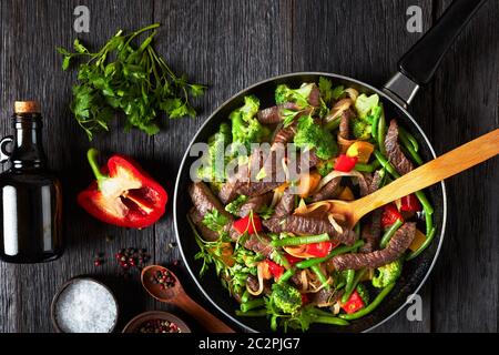 Fajita strisce di manzo con verdure: Peperoni dolci gialli e rossi, prezzemolo, cipolla, fagiolo verde e broccoli serviti su una padella con ingredienti su una d Foto Stock