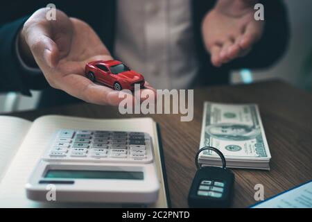 L'agente di vendita spiega il contratto di acquisto di una nuova auto al cliente e il pagamento delle rate. Foto Stock