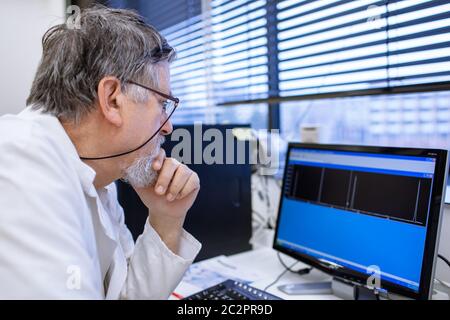 Maschio senior researcher di effettuare attività di ricerca scientifica in un laboratorio (SHALLOW DOF; dai toni di colore immagine) Foto Stock