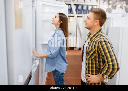 Coppia di famiglia che sceglie il frigorifero nel negozio di elettronica. Uomo e donna che acquistano elettrodomestici sul mercato Foto Stock
