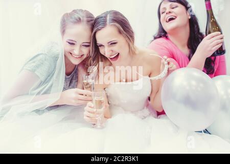 Sposa e bridesmaids avere divertimento e bere in previsione di jolly buon tempo mentre l'acquisto di abiti da sposa Foto Stock