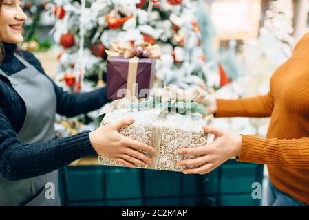 Servizio di confezionamento venditore dà al cliente un regalo di Natale scatola. Acquirente ordinato un pacchetto di presente Foto Stock