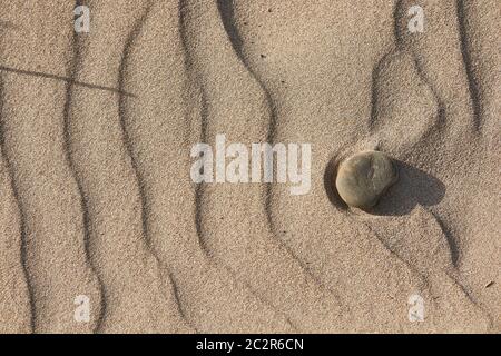 Consistenza di sabbia livellata dal vento con alcuni ciottoli Foto Stock