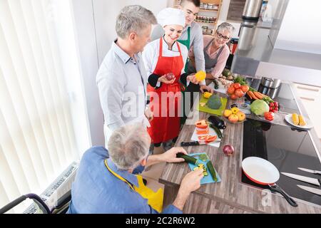 Dietista che spiega alla classe in cucina di addestramento la gioia delle verdure e del mangiare sano Foto Stock