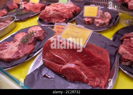 Tagli di carne cruda di vitello esposti in un banco freddo con etichette di prezzo pronte per la vendita nel macellaio. Foto Stock