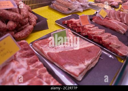 Tagli di carne cruda di vitello esposti in un banco freddo con etichette di prezzo pronte per la vendita nel macellaio. Foto Stock