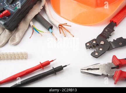 Per elettricista strumenti. Hardhat, multimetro, pinze, taglierina, cavi, ecc. Foto Stock
