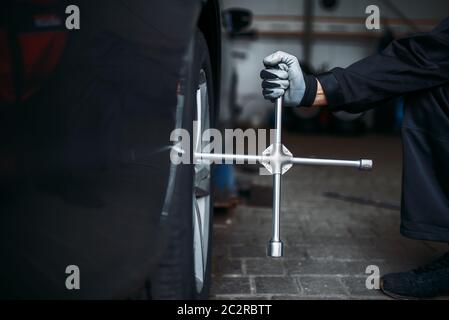 Ruota per auto con chiave, concetto di manutenzione pneumatici, nessuno. Attrezzi e attrezzature per la riparazione di pneumatici per automobili, ispezione del veicolo in officina Foto Stock