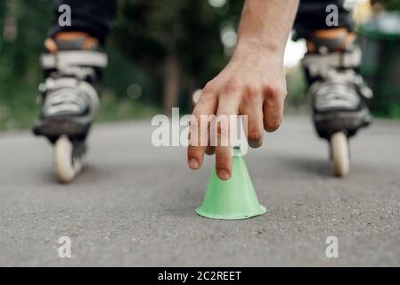 Pattinaggio a rotelle, pattinatore maschile mette i coni nel parco. Pattinaggio urbano, sport estremi attivi all'aperto, tempo libero per i giovani, pattinaggio a rotelle Foto Stock