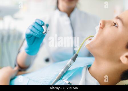 Guarnizione di tenuta del processo di installazione, odontoiatria pediatrica, bambini stomatologia. Dentista femmina denti di perforazione, clinica dentale Foto Stock