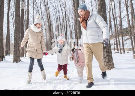 La famiglia felice in esecuzione nella neve Foto Stock