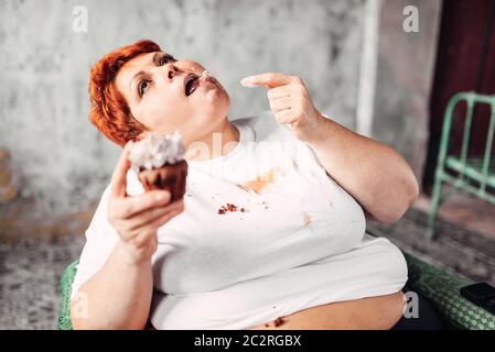 Donna sovrappeso mangia la torta dolce, la pigrizia e l'obesità. Cibo malsano mangiare, femmina grassi Foto Stock
