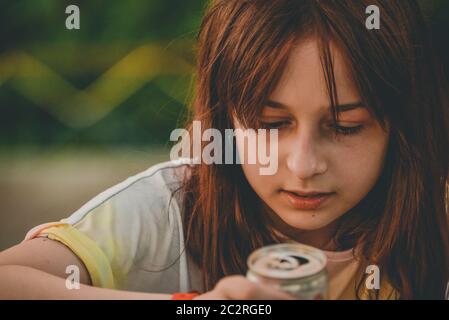 Giovane ragazza bere acqua. Teen ragazza beve con un ferro può Foto Stock