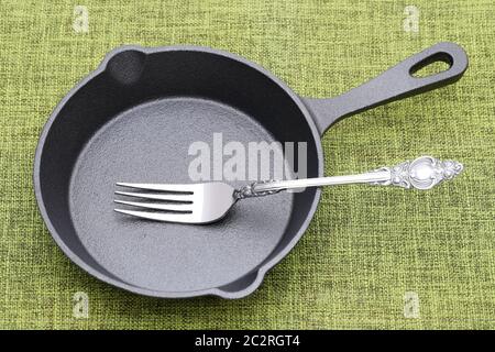 Vuoto ferro piccola padella con la forcella della tabella Foto Stock