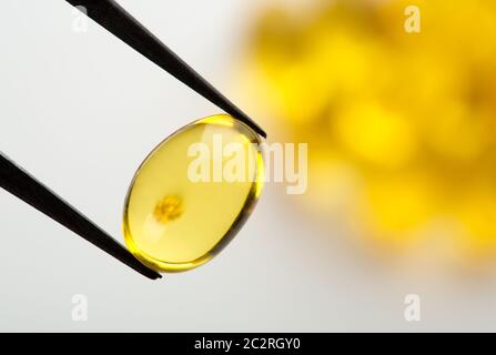 Primo piano di una pinzetta azienda giallo pillola di gel Foto Stock