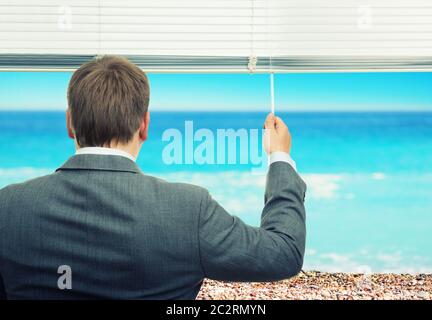 Imprenditore guardando il mare dalla finestra Foto Stock