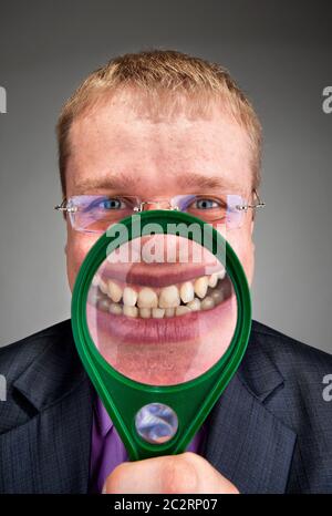 Happy businessman sorridente a voi attraverso la lente di ingrandimento Foto Stock