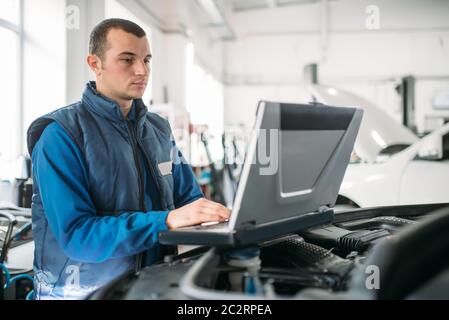 Ingegnere calcolatore rende la diagnostica della vettura in auto service. Cablaggio del veicolo ispezione Foto Stock