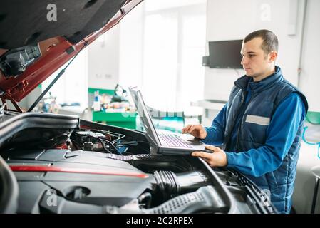 Ingegnere calcolatore rende la diagnostica della vettura in autoservice. Cablaggio del veicolo ispezione Foto Stock