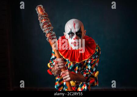 Mad sanguinosa clown con la mazza da baseball. L'uomo con il trucco in costume di halloween, zombie Foto Stock