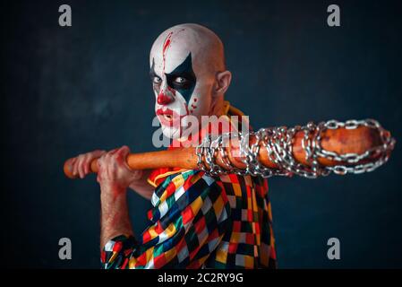 Mad sanguinosa clown con la mazza da baseball. Uomo con scary trucco in costume di halloween Foto Stock