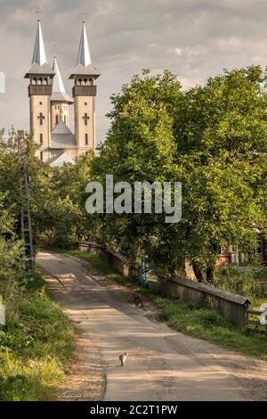 Un tranquillo vicolo che conduce alla chiesa moderna nel villaggio di Breb, Maramureş, Romania Foto Stock