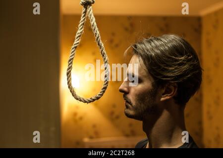 Uomo disperato che si prepara a suicidarsi. Uomo depresso con un cappio di corda. Foto Stock