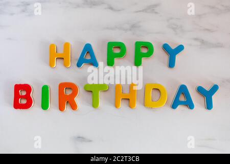 Happy Birthday parole scritte con lettere colorate su sfondo in marmo, vista dall'alto Foto Stock