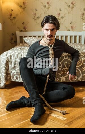 Uomo stressato con anello intorno al collo che si siede su pavimento di legno. Foto Stock