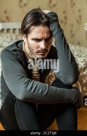 Uomo stressato con anello intorno al collo che si siede su pavimento di legno. Foto Stock