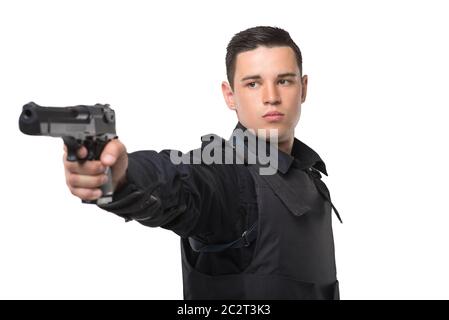 Poliziotto mira con una pistola, nero uniforme con una blindatura corporea, sfondo bianco, vista frontale. Cop in munizioni speciali Foto Stock