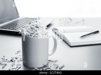 Coppa piena di carta tagliuzzata e laptop, notebook, penna Foto Stock